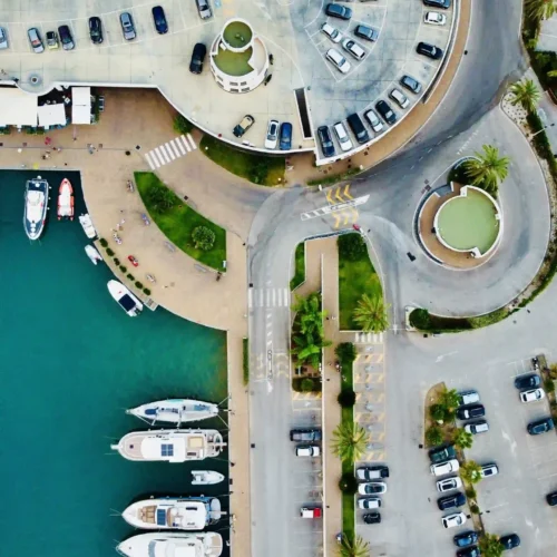 Vista aerea di un porto turistico vicino a Torino, con yacht ormeggiati lungo il molo e un parcheggio con auto, perfetto per riprese video a Torino, video corporate e documentario breve per video Torino.
