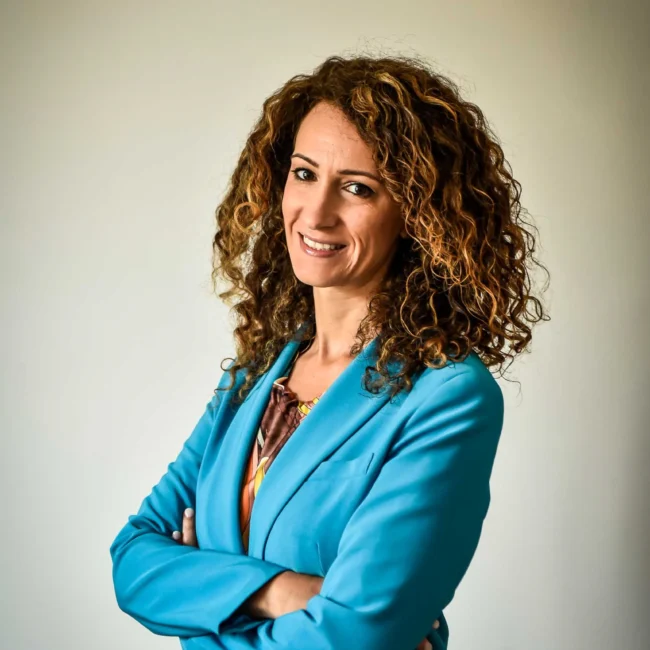 Ritratto professionale di una donna con giacca blu e sorriso luminoso, perfetto per un fotografo per Instagram che realizza foto profilo LinkedIn di alta qualità.