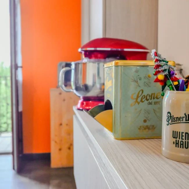 Foto immobili di un angolo cucina con elettrodomestici rossi, contenitori decorativi e vista su un balcone, opera di un fotografo per agenzia immobiliare.