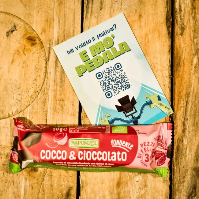 Foto professionale per siti web di una barretta di cioccolato e cocco Rapunzel, su un tavolo di legno, realizzata da un fotografo per Instagram