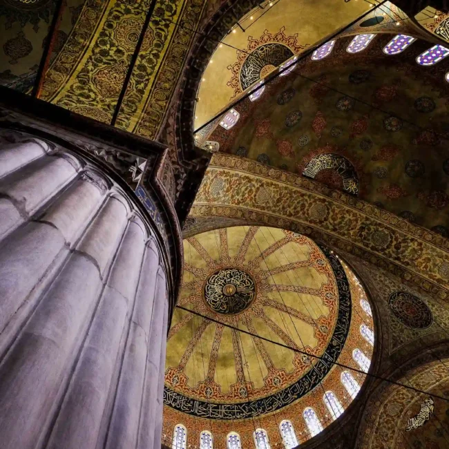 Interno grandioso di una moschea con cupole ornate e colonne imponenti, ideale per viaggi per fotografi che esplorano arte sacra e dettagli architettonici.