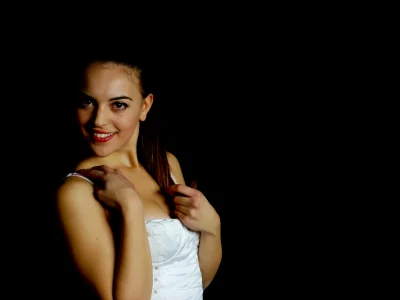 Vista laterale di una modella con corsetto bianco e jeans, posa elegante in un servizio fotografico di moda, sfondo nero. (book fotografici, servizi fotografici di moda)