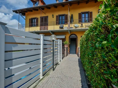 Foto immobili di un balcone esterno con ringhiera in ferro, vista su un giardino e edificio giallo, catturata da un fotografo per agenzia immobiliare.